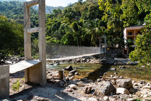 pedestrian bridge crossing river after flooding in rural Puerto Vallarta