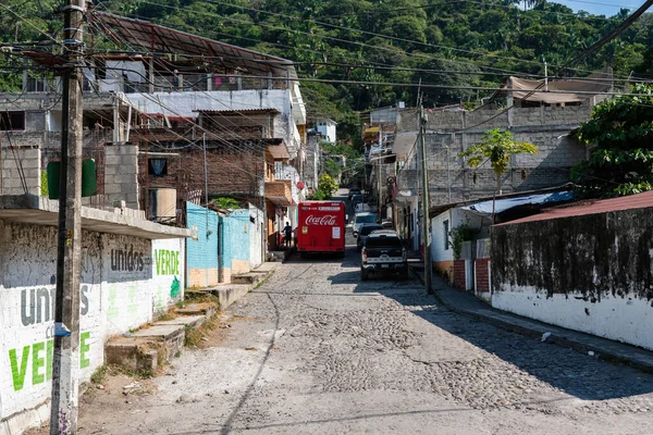 red truck stops in hillside brick street of rural Puerto Vallarta with homes and shops on both sides
