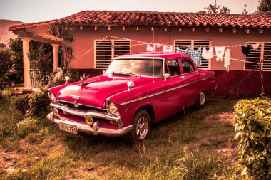 Viales, Küba - 09 Temmuz 2018: Eski bir klasik Amerikan arabası, parlak krom ve kırmızı renkli ev yakınlarında kurutma bezleri ile birlikte park edilmiş..