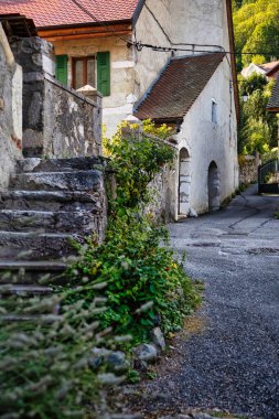 Menthon Aziz Bernard, Fransa - 10 Eylül 2020: Taşlı tarihi bir Fransız köyü manzarası, pencerelerin önündeki kepenkler ve yuvarlak kapılı kemerler