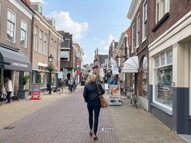 Voorburg, Hollanda - 04 Ağustos 2021: Eski bir ortaçağ caddesinde Hollandalı tarihi evler ve o caddenin ortasında yürüyen bir kadın