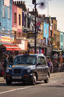 Londra, Birleşik Krallık - 18 Mart 2009: Klasik bir Londra taksisi renkli Camden yol pazarını geçti