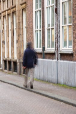 Lahey, Hollanda - 29 Ocak 2021: Küçük bir caddenin kaldırımında yürüyen ve tarihi binaları geçen gizemli bir adam