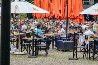 Lahey, Hollanda - 20 Ağustos 2021: Pek çok kişi Hollanda parlamentosunun önündeki meydanda bir restoranın terasında oturuyor
