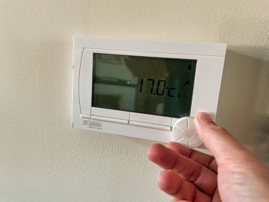 Den Haag, Hollanda - Kasım 04 2021: Bir kişinin eli bir termostatın sıcaklığını düşürür