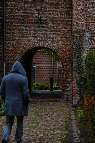 オランダのアメリカ砦 2020年10月25日 フード付きの男が歴史的な中世のオランダの都市の入り口の門に向かって夜に歩いています — ストック写真