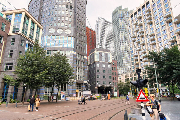 The Hague, Netherlands - August 20 2021 : people walking on the street with tram tracks with modern skyscrapers around