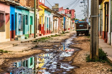 Trinidad, Küba - 15 Temmuz 2018: 18. yüzyılda hala taş kaldırımlı caddeleri olan eski bir İspanyol sömürge kasabası. Bir kız tropik muson yağmurlarından sonra karşıdan karşıya geçiyor.