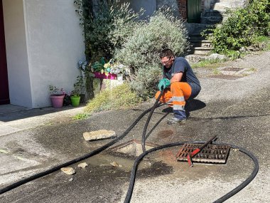 Menthon Saint Bernard, Fransa - 07 Eylül 2021: profesyonel bir işçi bir pompalı araba ve kanalizasyon borusunu temizlerken yüksek basınçlı hortumla meşgul