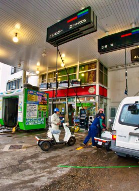 Tokyo, Japonya - 25 Kasım 2012: Japon benzin istasyonu, tavanındaki hortumlar kadar farklıdır. Bu durumda personel, mini arabanızı, arabanızı ya da scooterınızı doldurmanıza yardım eder..