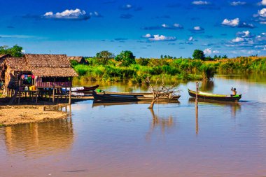 Bago, Myanmar - 02 Aralık 2012: Geleneksel Myanmar bambu kırsal evi ya da kırsal kesimde nehir ve uzun kuyruklu teknelerin bulunduğu cambaz ayaklıkları üzerindeki kulübe