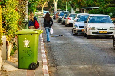 Tel Aviv, İsrail - 11 Kasım 2010: Tel Aviv 'de tahsilata hazır bir yerleşim sokağındaki kaldırımın kenarında yeşil bir konteyner duruyor.
