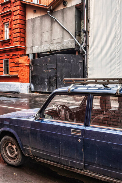 Moscow, Russia - September 12 2010: a vintage soviet lada car is parked in an alley next to an abandoned factory building near the Moskva river