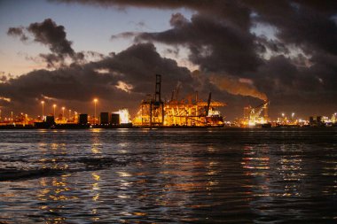 Rotterdam, Hollanda - 22 Kasım 2021: Deniz konteynırları geceleri aydınlanan dev vinçler tarafından gemilerden indiriliyor