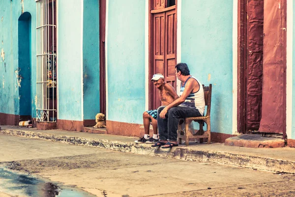 Trinidad, Küba - 15 Temmuz 2018: 18. yüzyılda kalan eski bir İspanyol sömürge kasabası. Yaşlı adamlar dışarıda koltuklarda oturup konuşuyorlar..