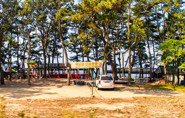 Incheon, Güney Kore - Haziran 09 2015: Deniz kenarındaki birkaç Kore restoranı ve ağaçların altındaki plaj