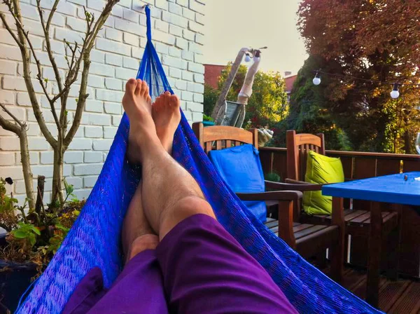 Adam yalın ayak yatıyor ve hamakta kestiriyor.