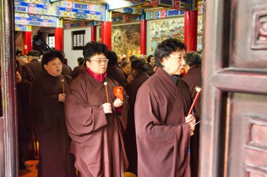 Chengdu, Çin - 29 Kasım 2009: Dua eden uzun bir insan kuyruğu, elleri bağlı ve kahverengi giysiler içinde kuyruğa giriyor.
