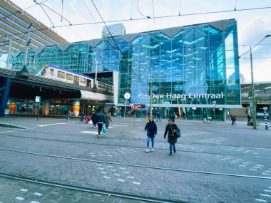 Den Haag, Hollanda - Kasım 05 2021: Birçok yolcu, tren, tren ve tramvay istasyonlarının birleştiği modern terminal binasının önünden geçiyor.