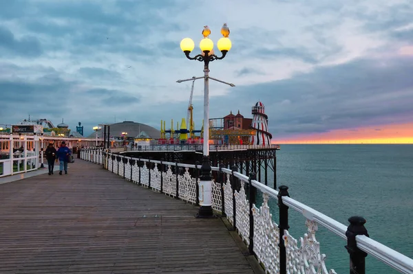 英国布莱顿 2022年3月4日 人们在英国海滨度假胜地的历史性码头上散步 带着霓虹灯 街机游戏和温暖的日落色 — 图库照片