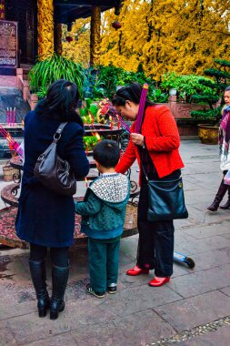 Chengdu, Çin - 29 Kasım 2009: Küçük bir çocuk tapınaktaki ibadetin işareti olarak ruhu aydınlatıyor