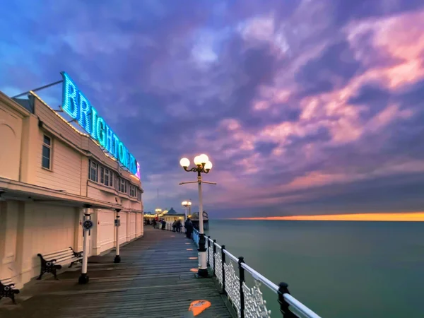 英国布莱顿 2022年3月4日 人们在英国海滨度假胜地的历史性码头上散步 带着霓虹灯 街机游戏和温暖的日落色 — 图库照片