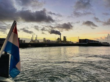 Rotterdam, Netherlands - November 22 2021 : a national dutch flag has been planted on a ship floating in an harbor at sunset