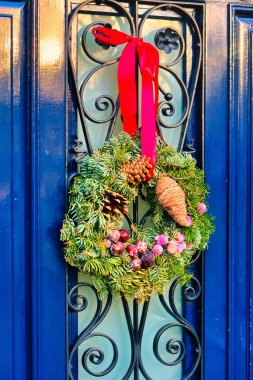 Den Haag, Netherlands - January 10 2022: a christmas wrench made of fresh pine tree is hanging on a red ribbon on a front door of a home