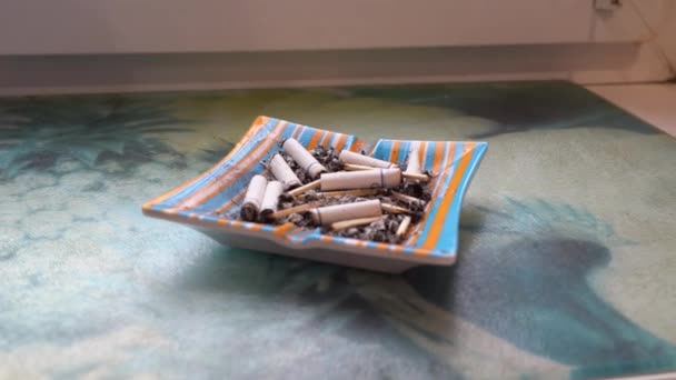 Ένα τασάκι γεμάτο τσιγάρα στέκεται κοντά στο παράθυρο. — Αρχείο Βίντεο
