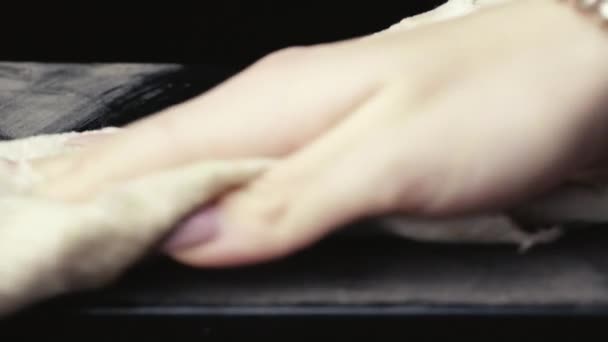 Limpieza de polvo con una hermosa mano femenina de una superficie negra. — Vídeos de Stock