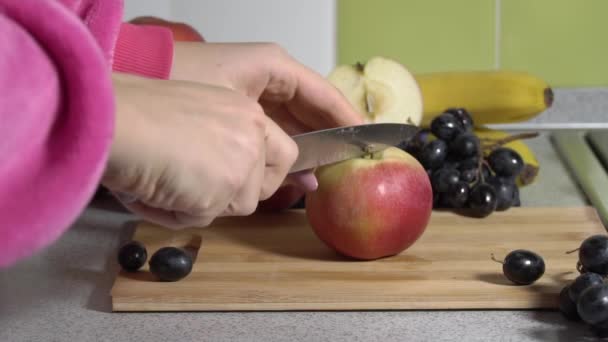 Vrouw handen snijden een appel op een plank met een mes. — Stockvideo