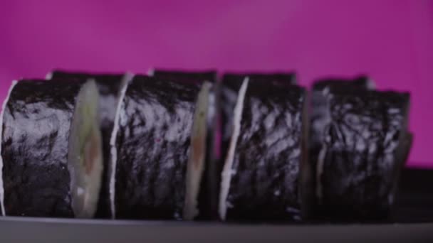 Суши-ролл на розовом фоне — стоковое видео