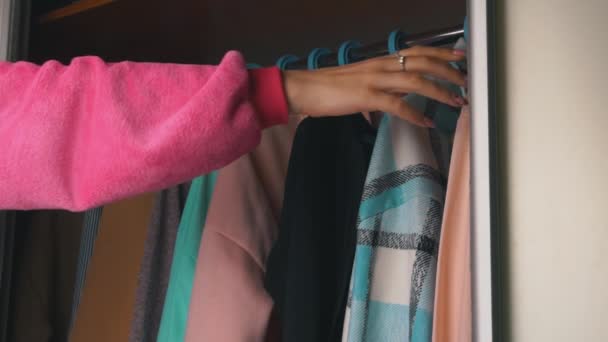 Dziewczyna wybiera rzeczy w szafie w domu — Wideo stockowe
