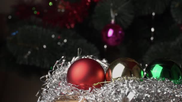 Πρωτοχρονιάτικα παιχνίδια βρίσκονται στο λαμπερό Tinsel Στο φόντο του χριστουγεννιάτικου δέντρου. — Αρχείο Βίντεο