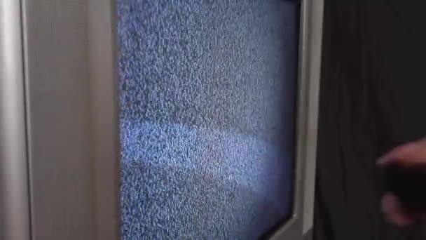 Девочка меняет каналы на старом телевизоре с шумом — стоковое видео