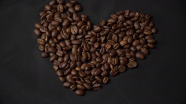 Кофе бобы лежат в виде сердца, их женская рука очищает их — стоковое видео
