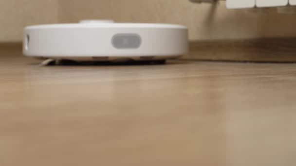 Fehér robot porszívó eltávolítja a törmeléket a laminált — Stock videók