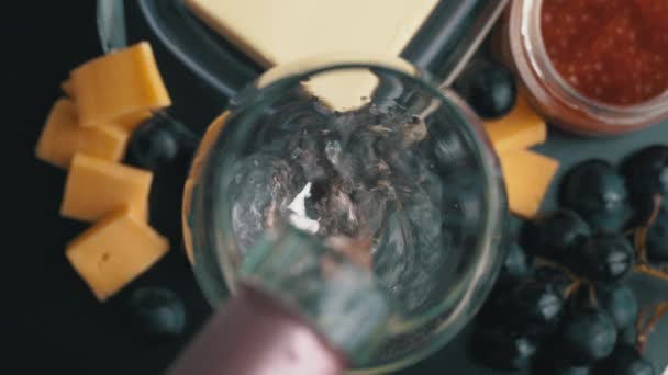 Rozenwijn wordt gegoten in een glas met snacks — Stockvideo