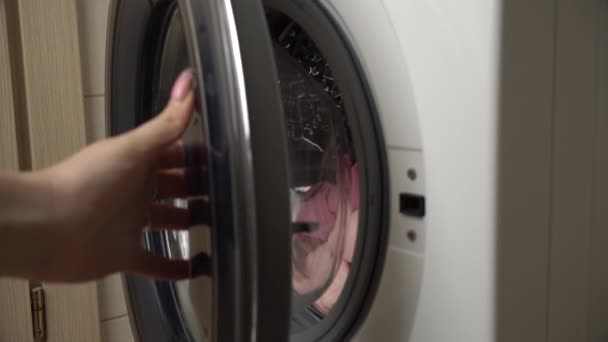 As mãos das mulheres colocam roupas em uma máquina de lavar moderna — Vídeo de Stock