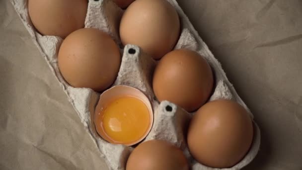 Złamane jajko leży w kontenerze wśród całych jaj. — Wideo stockowe