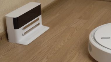 Beyaz Robotik Elektrikli Süpürge Temizleyicisi Temizliği bitirdi ve Şarj İstasyonuna Sürüyor