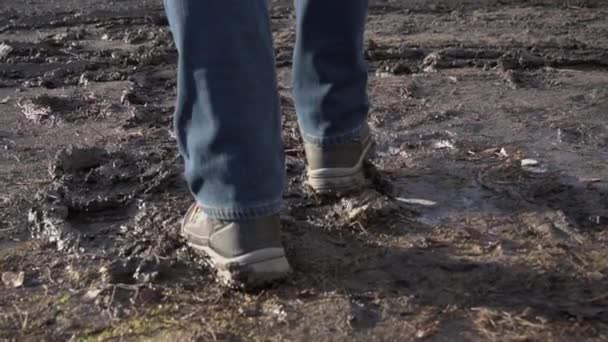 L'homme en bottes marche dans la boue, éclaboussures d'une flaque à Slowmo — Video