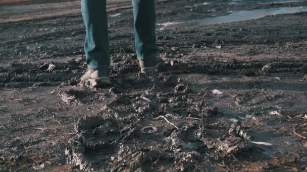 Man i stövlar går genom leran, plaska från en pöl i Slowmo — Stockvideo