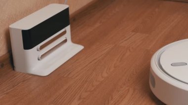 Beyaz Robotik Elektrikli Süpürge Temizleyicisi Temizliği bitirdi ve Şarj İstasyonuna Sürüyor