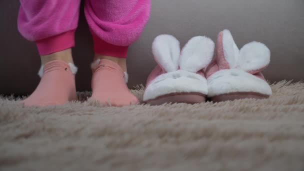 Jonge vrouw stapt uit bed en zet op roze slippers in de ochtend — Stockvideo