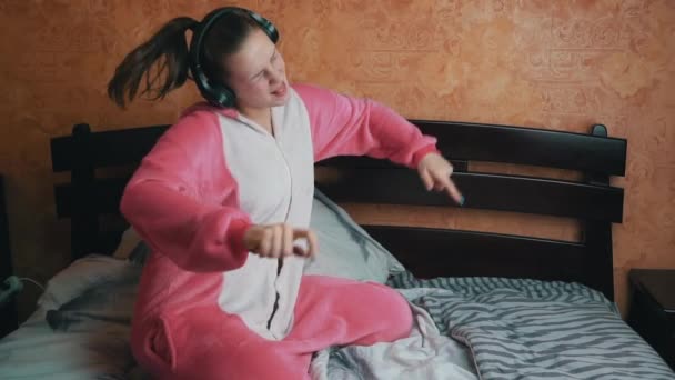 Girl in Pyjamas on the Bed Écoute de la musique avec des écouteurs et des danses Slowmo — Video
