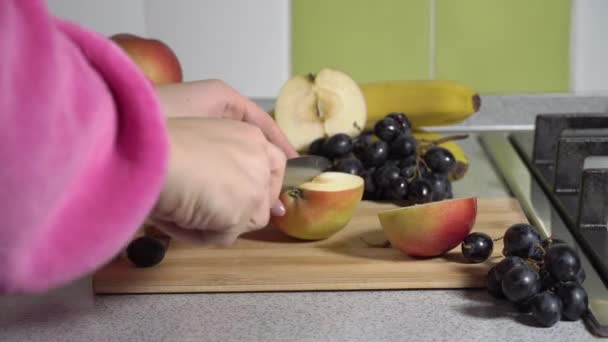 Mãos de mulher cortam uma maçã em uma prancha com uma faca. — Vídeo de Stock
