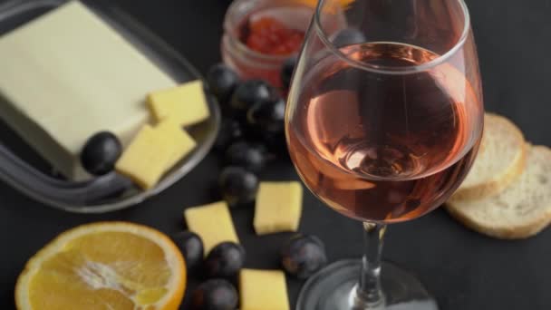 Szklanka różowego wina wiruje z przekąskami — Wideo stockowe