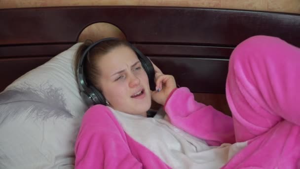Girl in Pyjamas on the Bed Écoute de la musique avec des écouteurs et des danses — Video