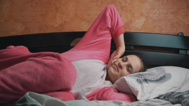 Sonriente chica en pijama se despierta por la mañana y abre los ojos — Vídeo de stock